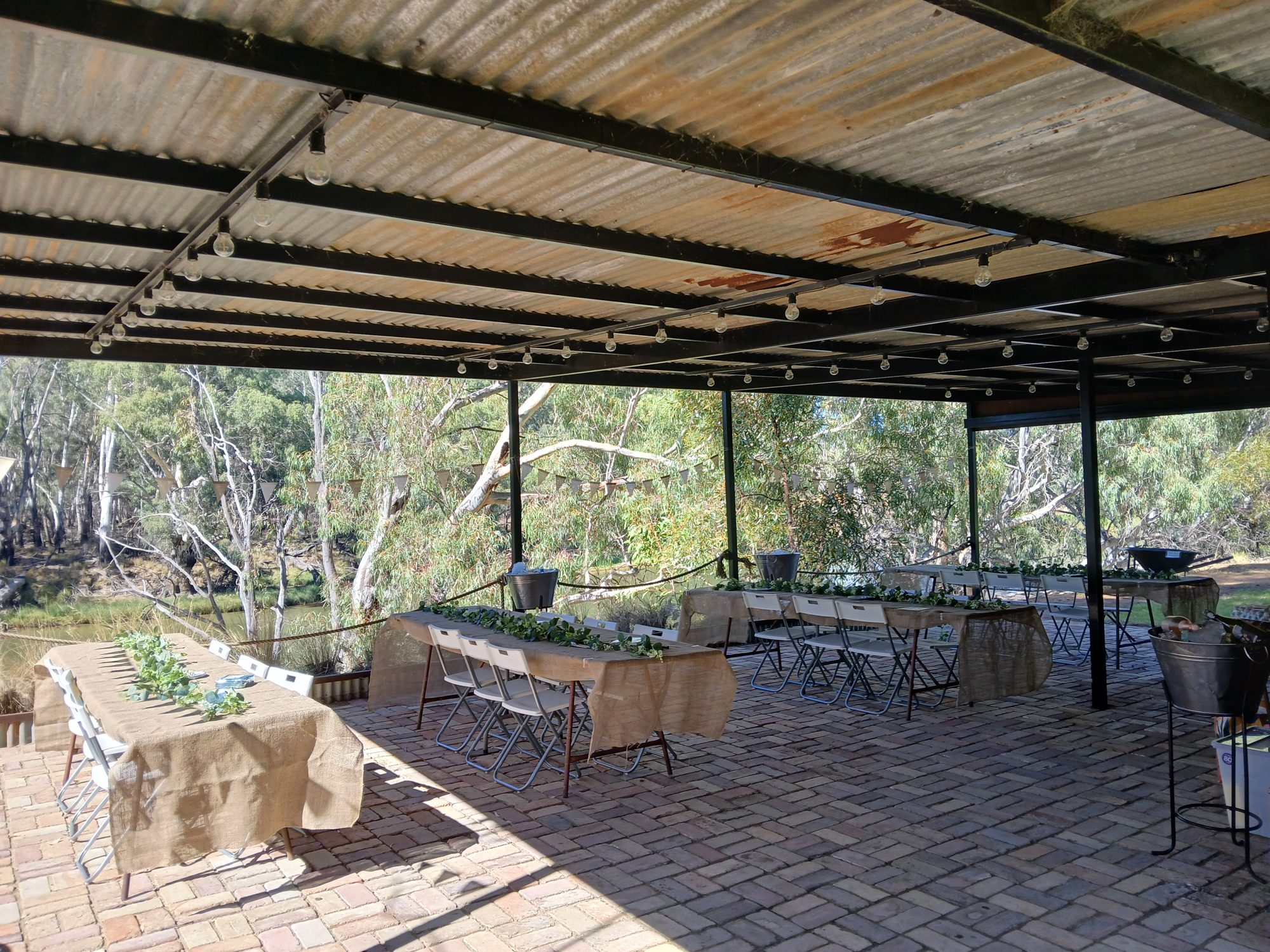 Riverbank building set with long tables for a reception, overlooking the river